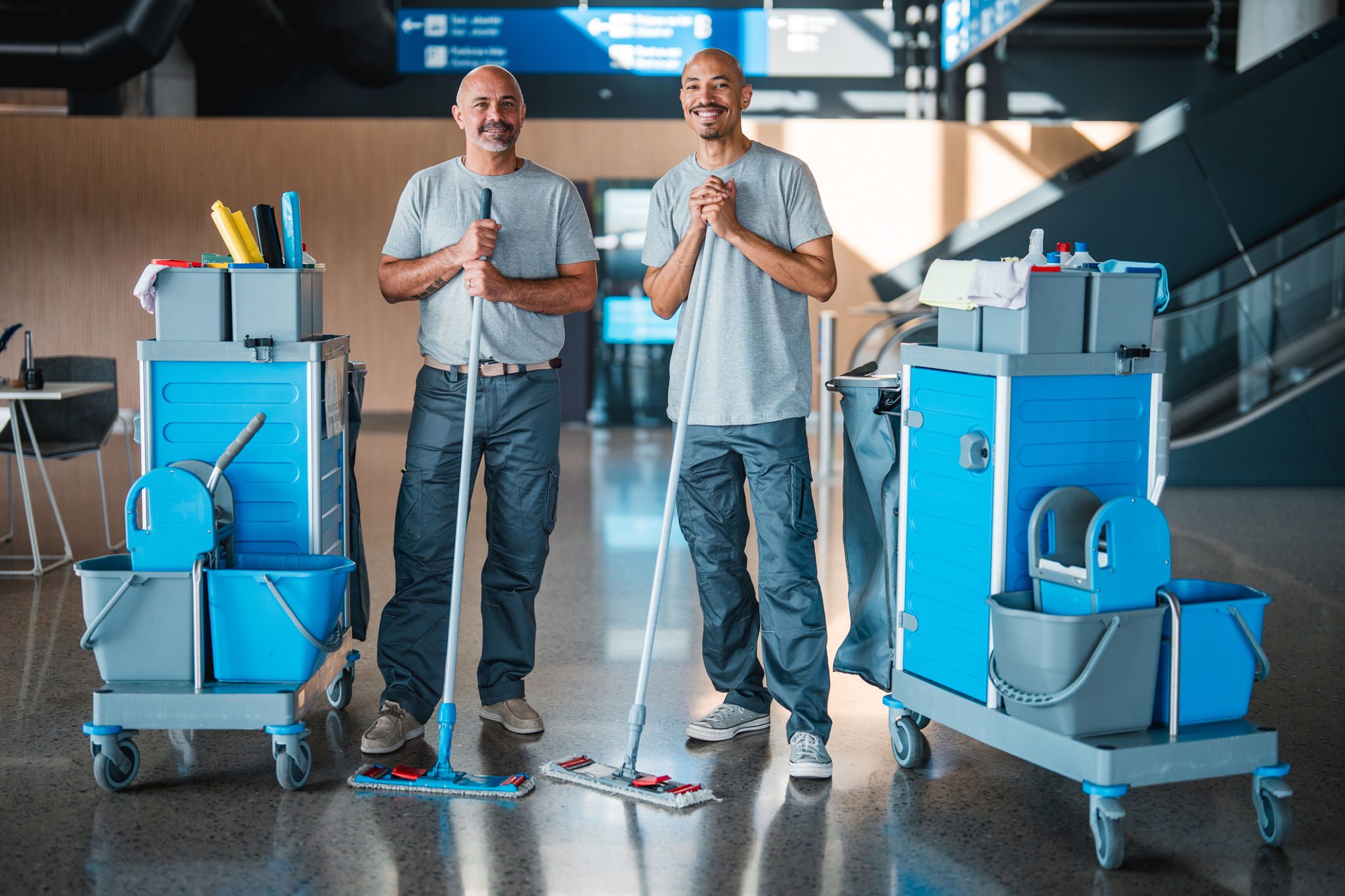 Smiling custodians holding mops indoors